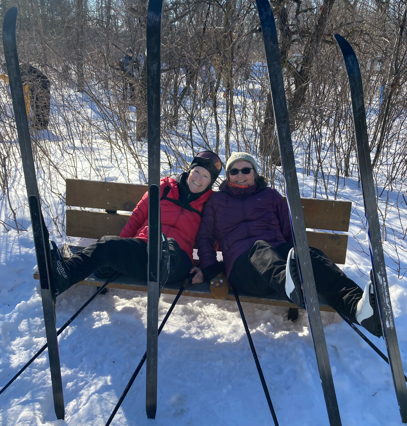 two women (Sarah and Rose) on a bench relazing with skis n the foreground