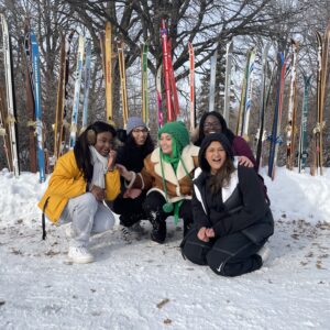 five women in front of a lineup of skis