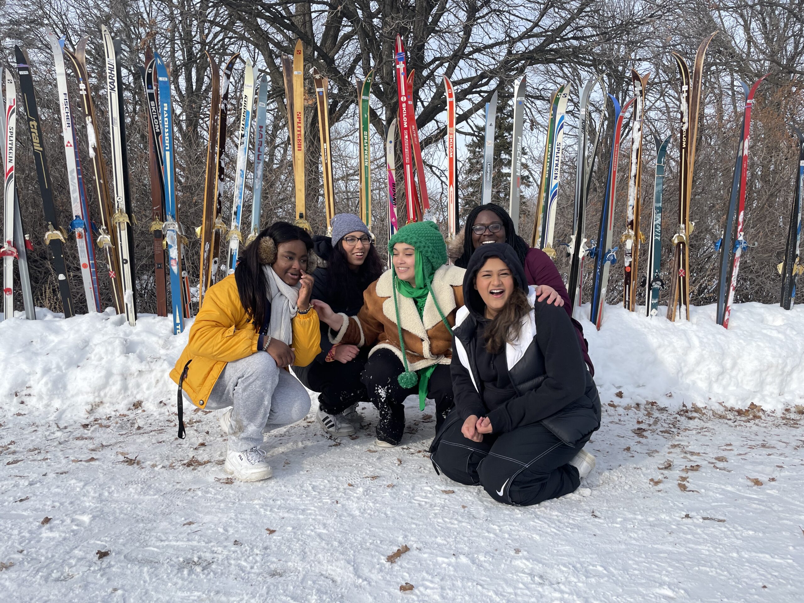 five women in front of a lineup of skis