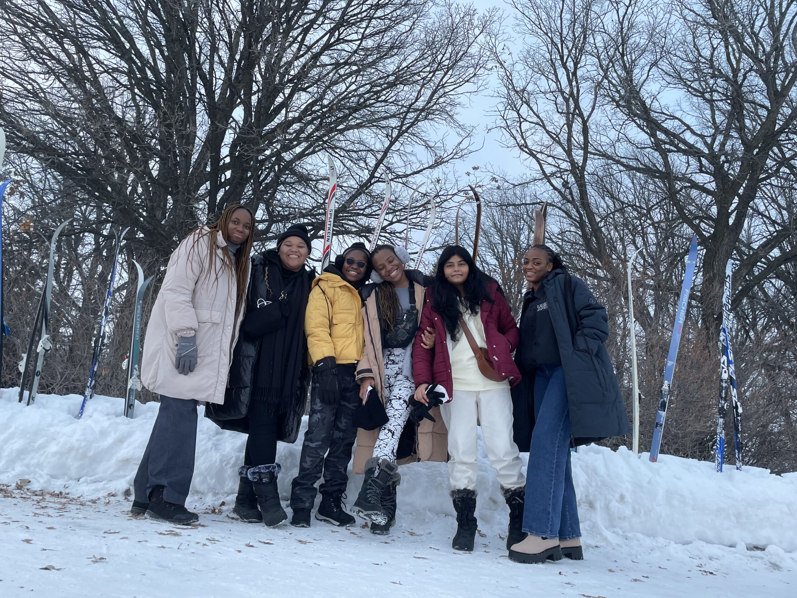 five women standing in front of skis