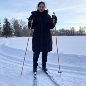 Adult woman in a long navy jacket on skis