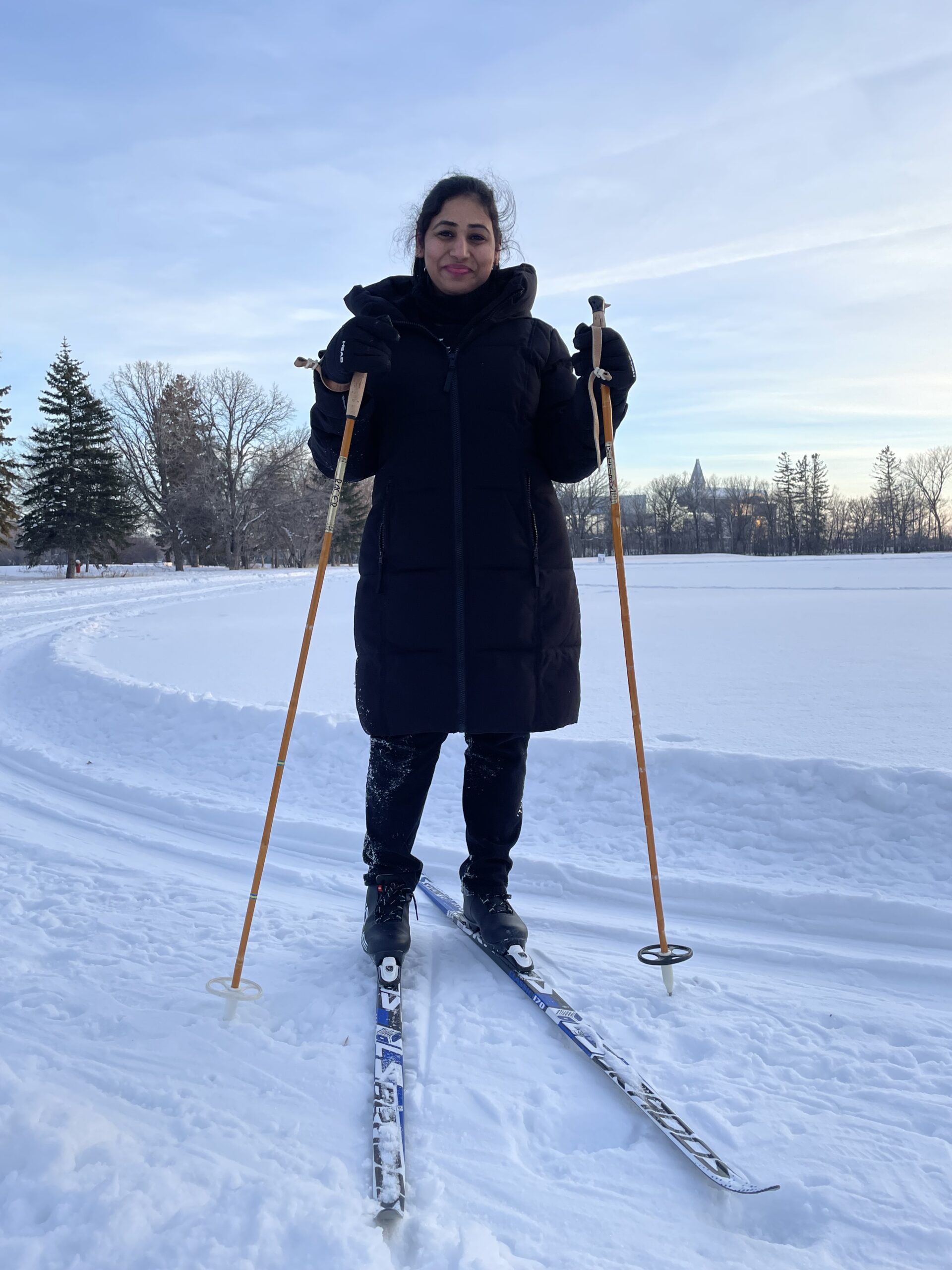 Adult woman in a long navy jacket on skis