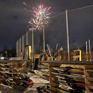 A rack full of skis with fireworks in the background.
