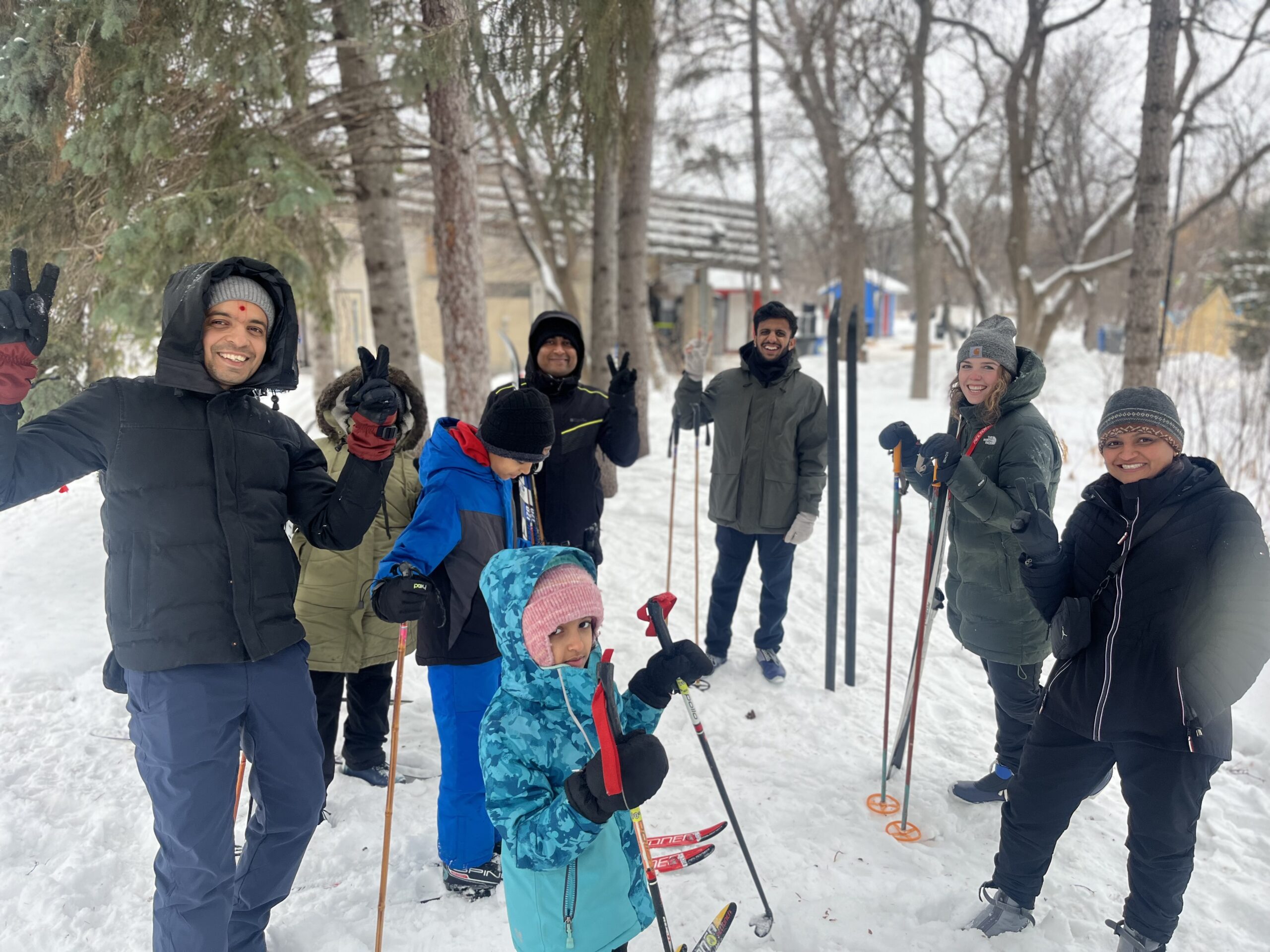 A large group of people standing in a circle with skis smiling