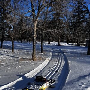 An yellow ski trail track setter in front of a curving ski trail